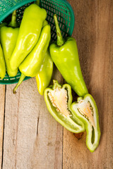 Green peppers in a basket on a wooden floor