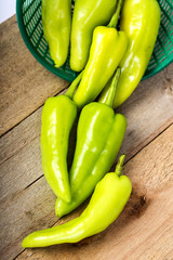 Green peppers in a basket on a wooden floor