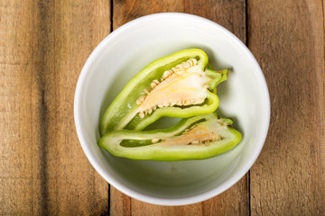 Green peppers in cup on a wooden floor