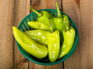 Green peppers in a basket on a wooden floor