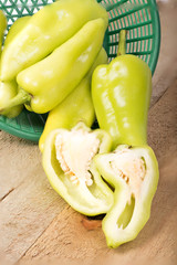 Green peppers in a basket on a wooden floor