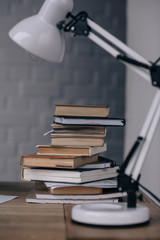 close-up shot of stacked books and table lamp on work desk
