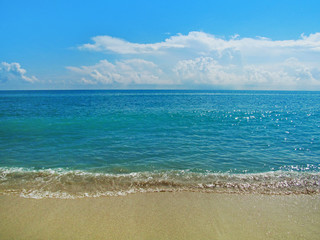 Fototapeta premium Sand beach and water in summer sunny day. Beautiful ocean view with a small smooth waves on the beach in Miami, Florida, USA.Travel vacation concept.
