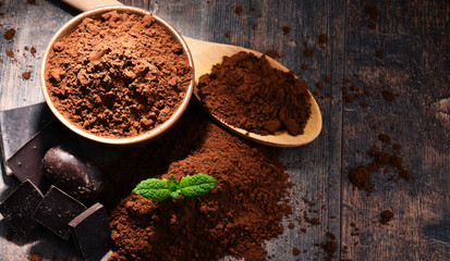 Composition with bowl of cocoa powder on wooden table