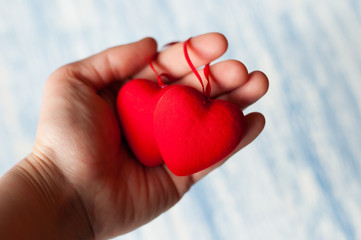 Two red hearts in one hand. Feast of St. Valentine's Day