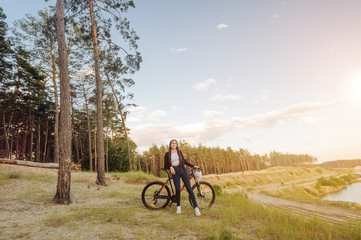 Obraz premium Young woman on a bicycle in the forest standing on road and looking to somewhere