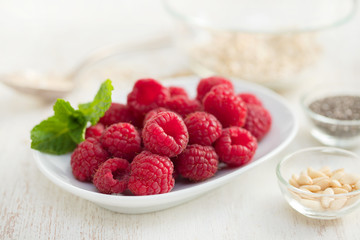raspberries on white dish on wooden background