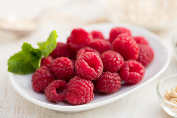 raspberries on white dish on wooden background