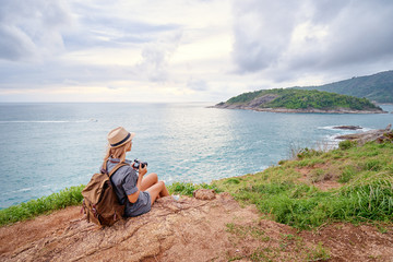 Travel and hobby. Pretty young woman with camera and rucksack enjoying the sea view.