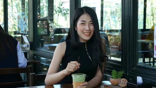 4k of young woman drinking ice green tea latte in the cafe