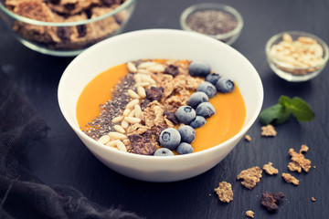 puree of mango with granola, chia and berries in white bowl