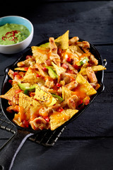Nachos with meat, vegetables and guacamole dip