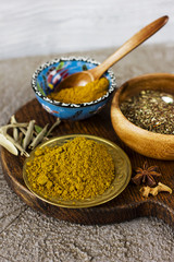 Different dry spices in bowls on a wooden Board on a concrete background