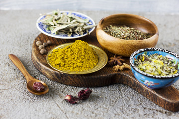Different dry spices in bowls on a wooden Board on a concrete background