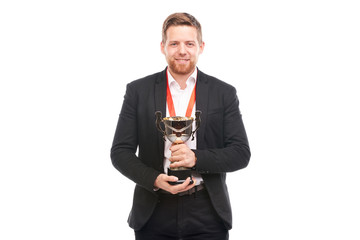 Portrait of confident young businessman wearing medal and holding trophy on white background