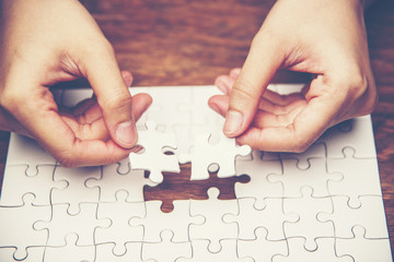 Close up of hand placing the last jigsaw puzzle piece, Hand holding missing jigsaw puzzle piece down in to the place, conceptual of problem solving, finding a solution.