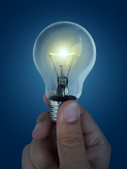 A man's hand holding an Light bulb open, isolated, on blue background