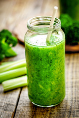 Green vegetable smoothie in glass at wooden background