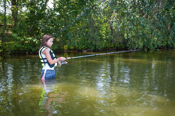 Fototapeta na wymiar Young teenage girl fishing in the water