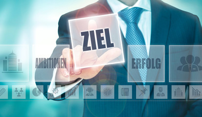 A businessman pressing a Aim "Ziel" button in German on a futuristic computer  display