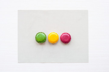 three different-colored round French macaron cookies on the table