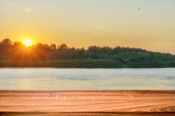 Fototapeta na wymiar Empty wooden table with summer background of riverside at sunset. Can be used for display or montage products