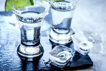 Silver tequila shots with lime and salt on gray stone background