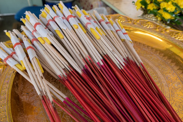 Incenses sticks and Candles  in golden tray for Praying in Buddhist Temple. Religion and travel in Thailand.
