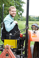 Fototapeta na wymiar Portrait Of Farmer Sitting On Tractor In Field