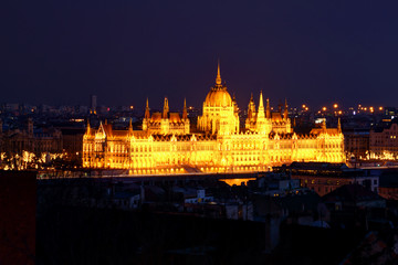 Obraz premium Panorama of Neo-Gothic Orszaghaz Parliament Building Hungarian legislative body seat at dusk illuminated by glowing yellow light on Danube riverbank Kossuth Square Pest Budapest Hungary Central Europe