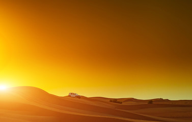 Offroad truck or suv riding dune in arabian desert at sunset. Offroad has been modified to be...