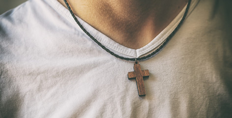 The wooden cross necklace on man's neck