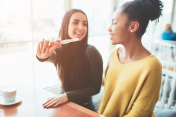 An intersting picture of two young girls where one of them is showing her pregnancy test with...