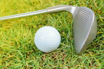 Golf clubs and golf ball on green grass background