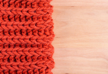 Fototapeta na wymiar Red knitted wool product, close up, on a light wooden background. 