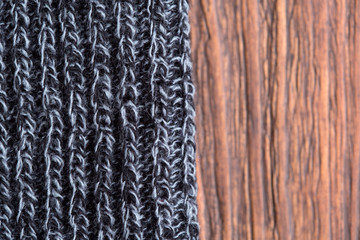 Gray knitted wool product, close up on a wooden background.
