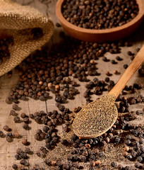 black ground pepper in a wooden spoon on a wooden background.rustic style