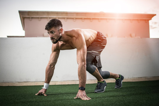 Young shirtless muscular man training before running outdoors. Warming up before a workout.