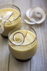 Pineapple smoothie with bananas, oatmeals and coconut milk, decorated with coconut chips, wooden breakfast tray