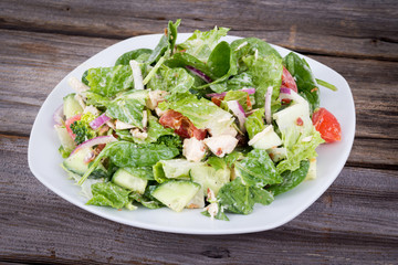 Chicken and vegetable salad with ranch dressing over wooden background table