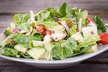 Chicken and vegetable salad with ranch dressing over wooden background table