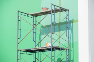 Scaffolding iron with green wall and paint bucket.