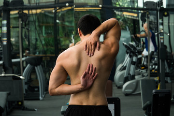 Fototapeta na wymiar Attractive young man stretching on his back in the gym before training