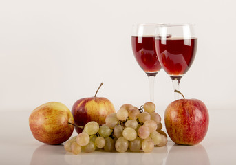 red apples, grapes, glass glasses with juice, wine on a white background