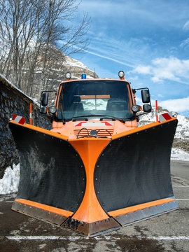 Small Orange Truck Using Snow Plow