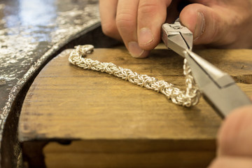 Silver jewelry craft making with men hands holding tools in a foreground