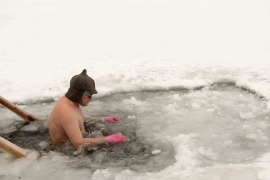 Crazy elderly Russian man, swimming in the ice-hole as President Putin on Lake Seliger. Feast of the Baptism of Jesus Christ. Pyatimorsk, a baptismal ice-hole near the church of St. Innocent.