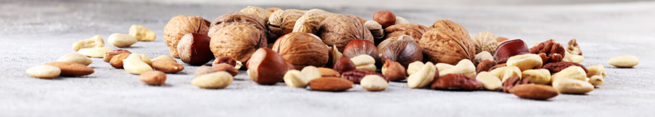 mixed nuts on grey background. Healthy food and snack. Walnut, pecan, almonds, hazelnuts and...