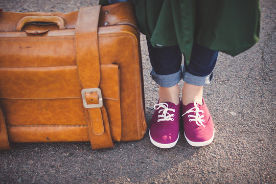 Girl foots in gumshoes with travel bag