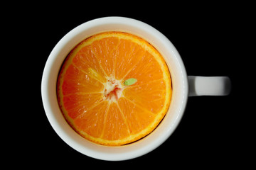 Orange slice in white cup with white tube isolated on black background
